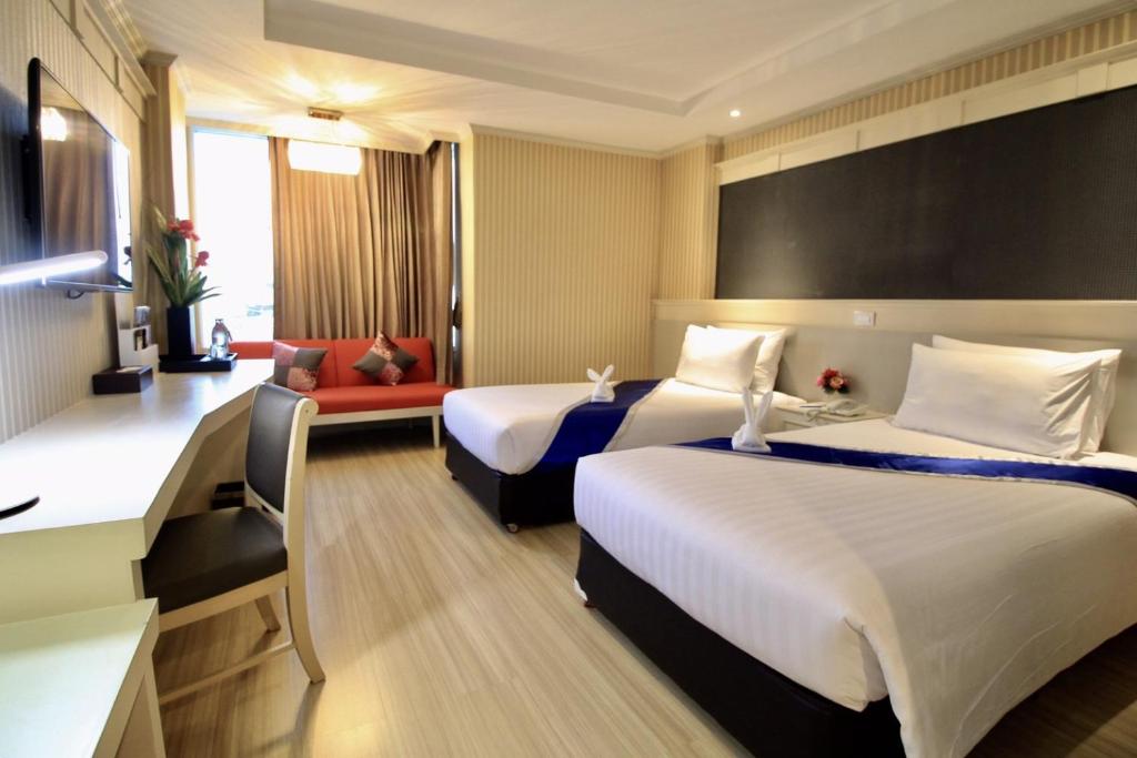 um quarto de hotel com duas camas e um sofá vermelho em โรงแรมวีวิช V Wish Hotel em Khon Kaen