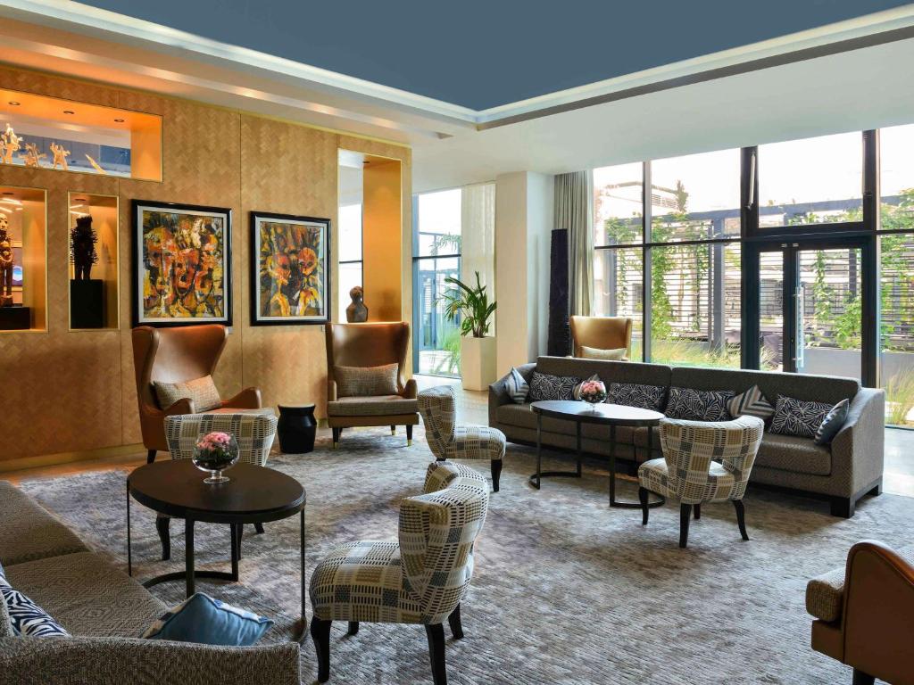 a living room with couches and tables and chairs at Mövenpick Hotel Abidjan in Abidjan