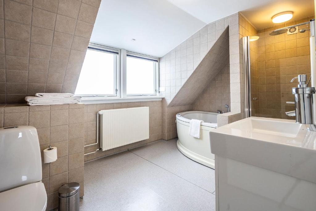 a bathroom with a tub and a sink and a toilet at HOTEL SØMA Ilulissat in Ilulissat