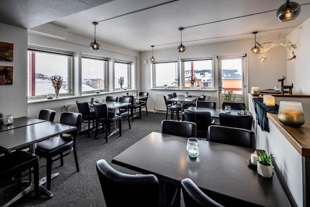 a restaurant with tables and chairs and windows at HOTEL SØMA Ilulissat in Ilulissat
