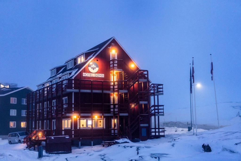 a large building in the snow at night at HOTEL SØMA Ilulissat in Ilulissat