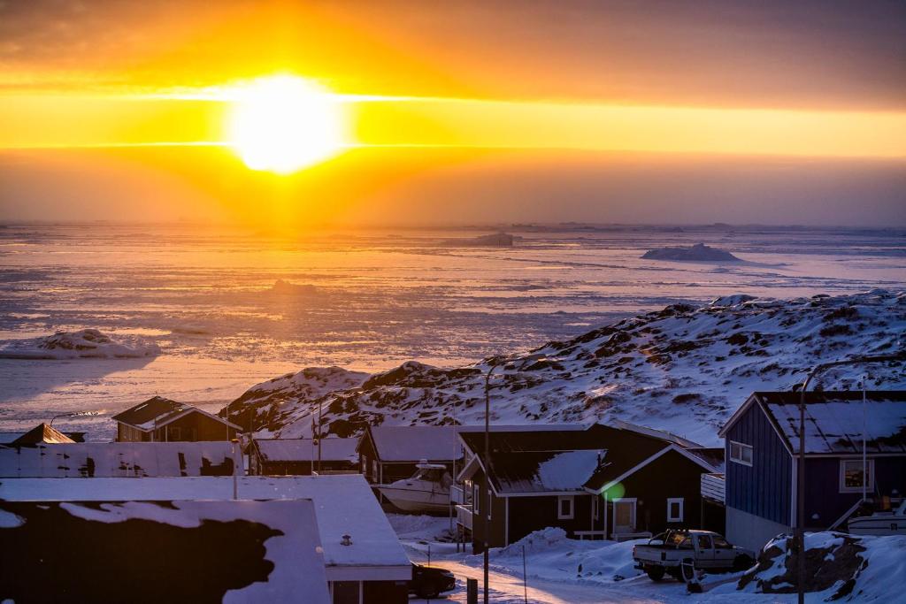 a winter sunset with the sun setting over the ocean at HOTEL SØMA Ilulissat in Ilulissat