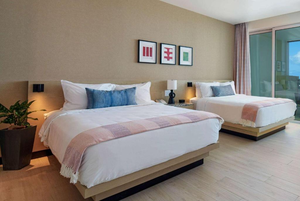 a hotel room with two beds and a window at Wyndham Grand Barbados Sam Lords Castle All Inclusive Resort in Saint Philip