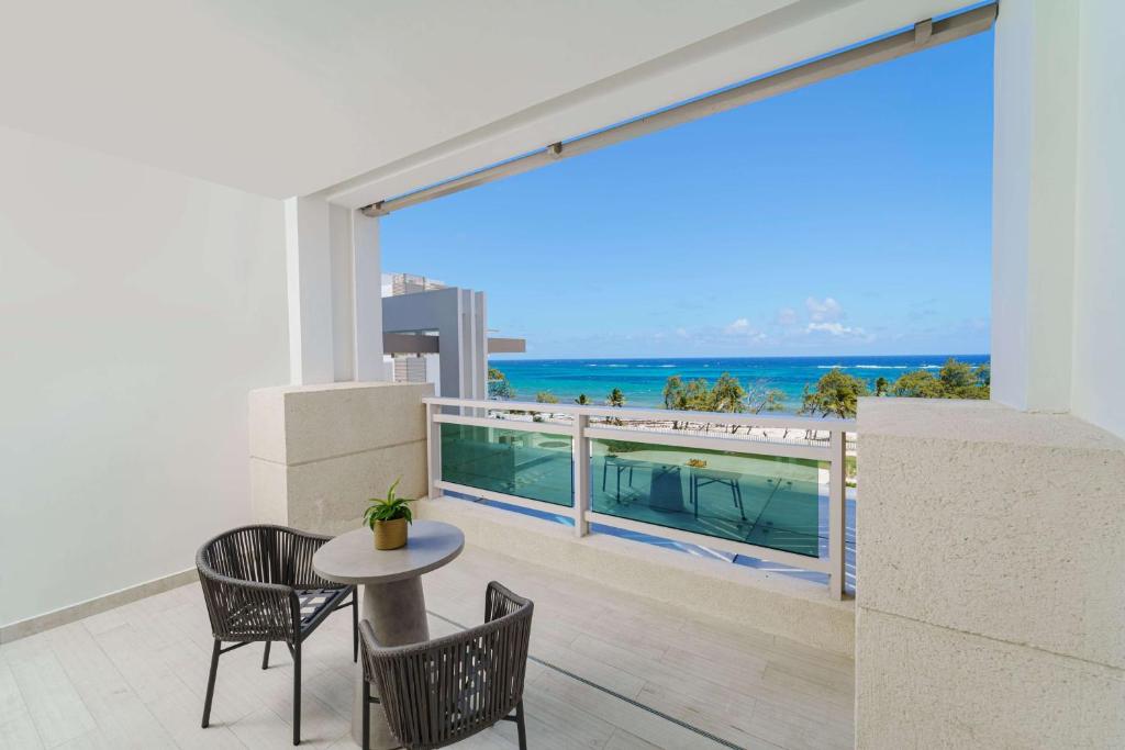 a balcony with a table and chairs and a view of the ocean at Wyndham Grand Barbados Sam Lords Castle All Inclusive Resort in Saint Philip