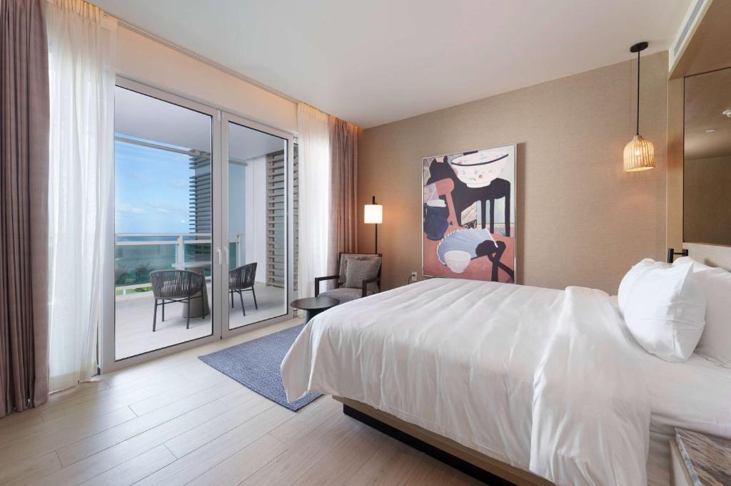 a hotel room with a bed and a balcony at Wyndham Grand Barbados Sam Lords Castle All Inclusive Resort in Saint Philip