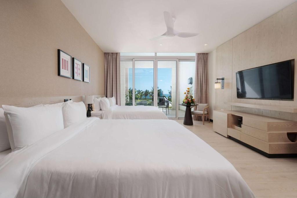 a bedroom with a large white bed and a flat screen tv at Wyndham Grand Barbados Sam Lords Castle All Inclusive Resort in Saint Philip