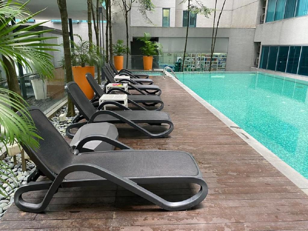 a row of lounge chairs next to a swimming pool at Mercu Summer Suite by Great Service in Kuala Lumpur