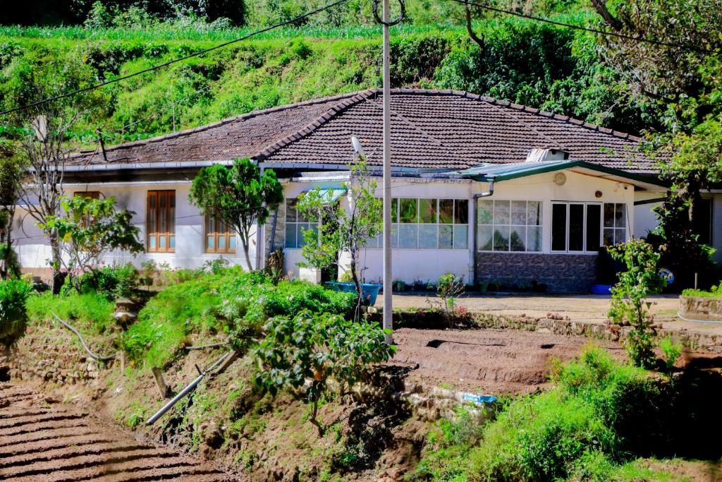 a white house with a garden in front of it at St Elmo Homestay in Nuwara Eliya