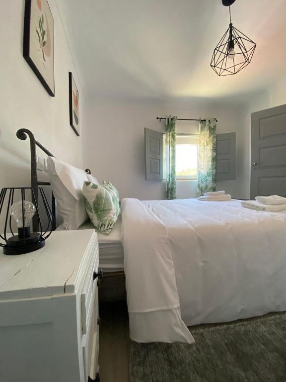 um quarto com uma cama branca e uma janela em Casa do Balcão em Mêda