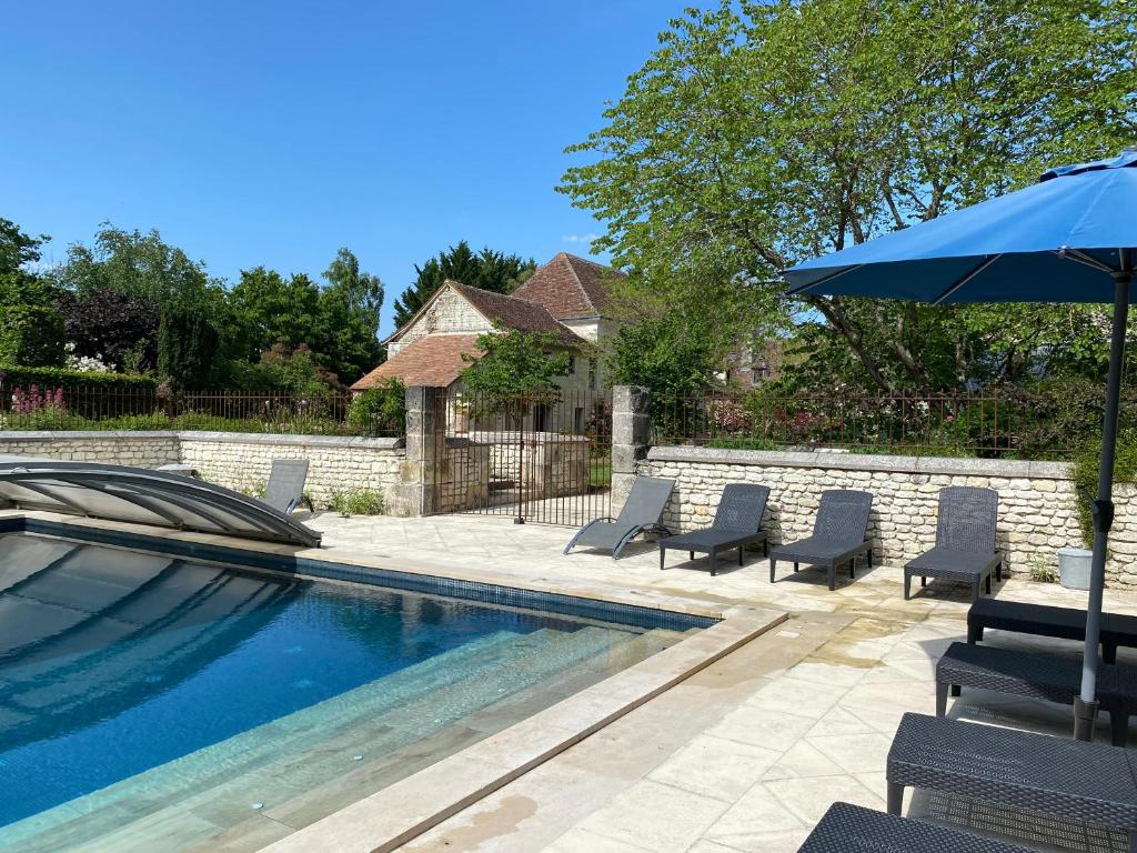 une piscine avec des chaises et un parasol dans l'établissement Gite logis de la COQUETIERE avec piscine, à Ports