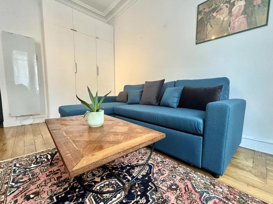 un salon avec un canapé bleu et une table basse dans l'établissement Charming Apartment Paris - Rentaway BnB, à Paris