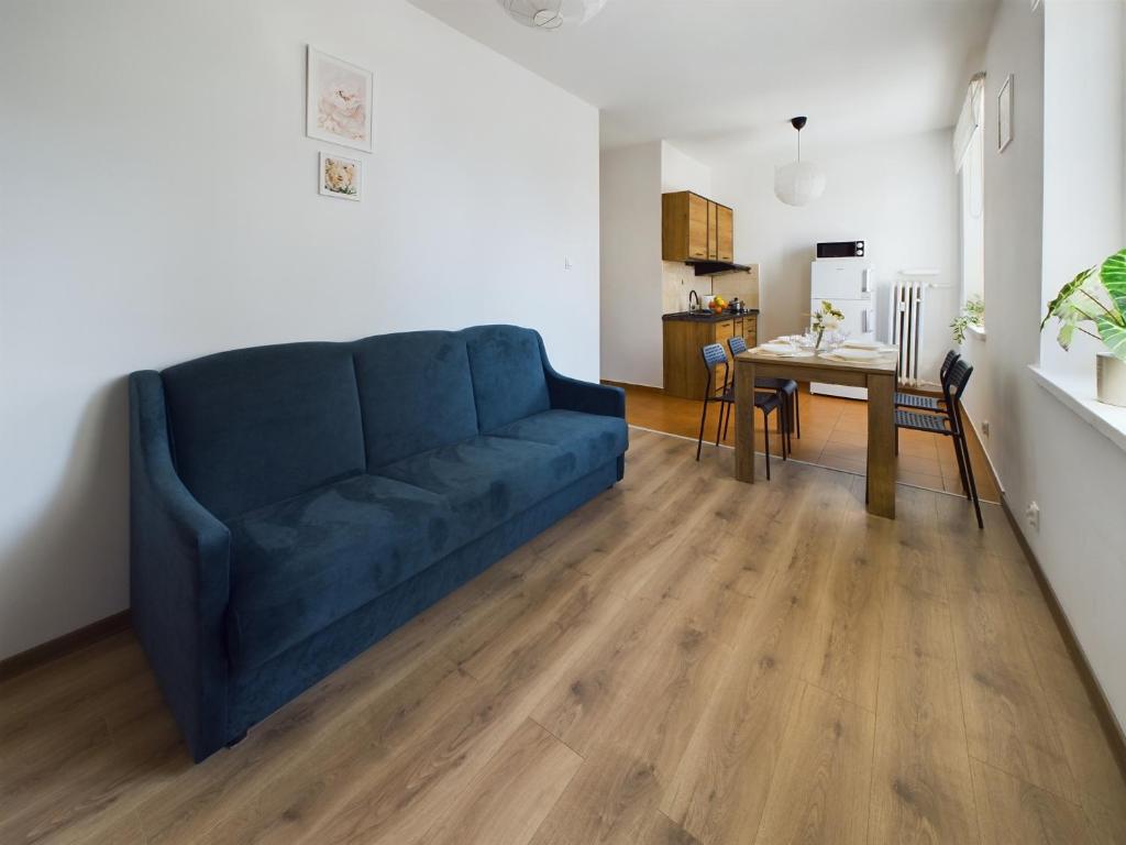 Sofá azul en la sala de estar con mesa en Gdynia City Centre Apartment Abrahama by Renters, en Gdynia