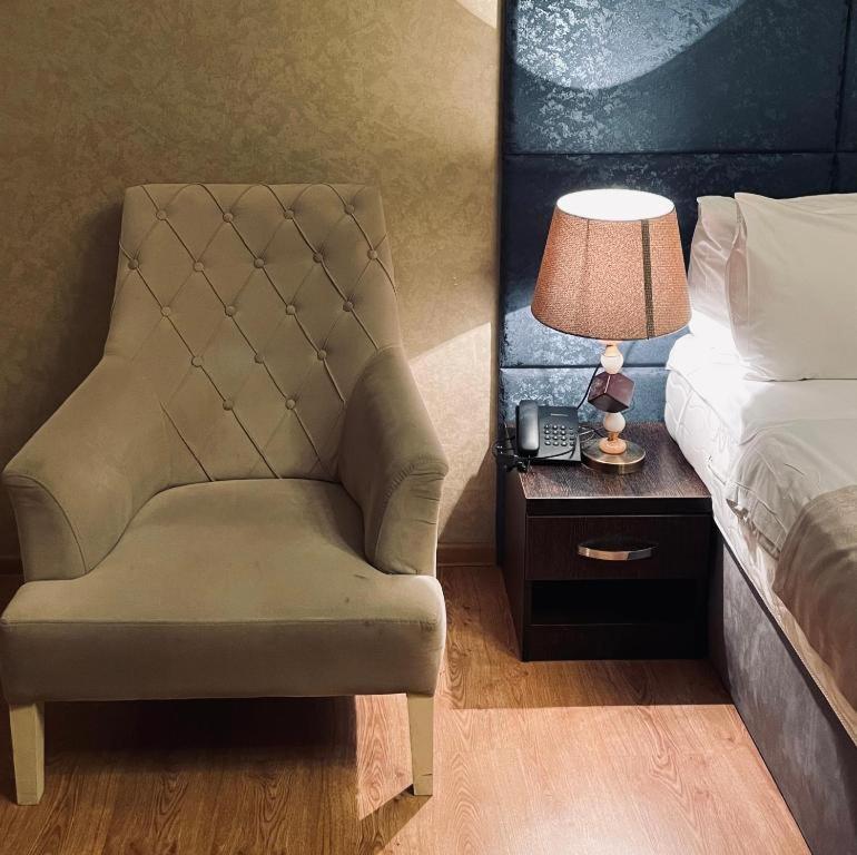 a bedroom with a chair and a bed and a lamp at Sherlock Hotel Baku in Baku