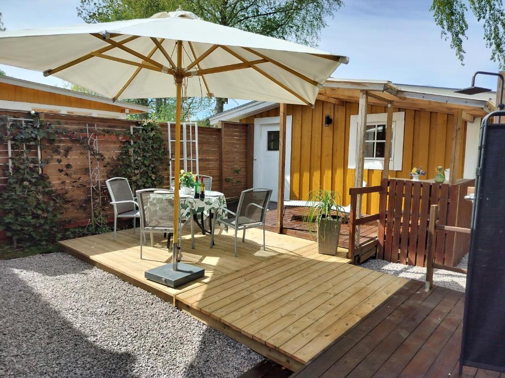 瑪麗斯塔德的住宿－Lilla Stugan, Sjötorp，木甲板上的桌子和遮阳伞