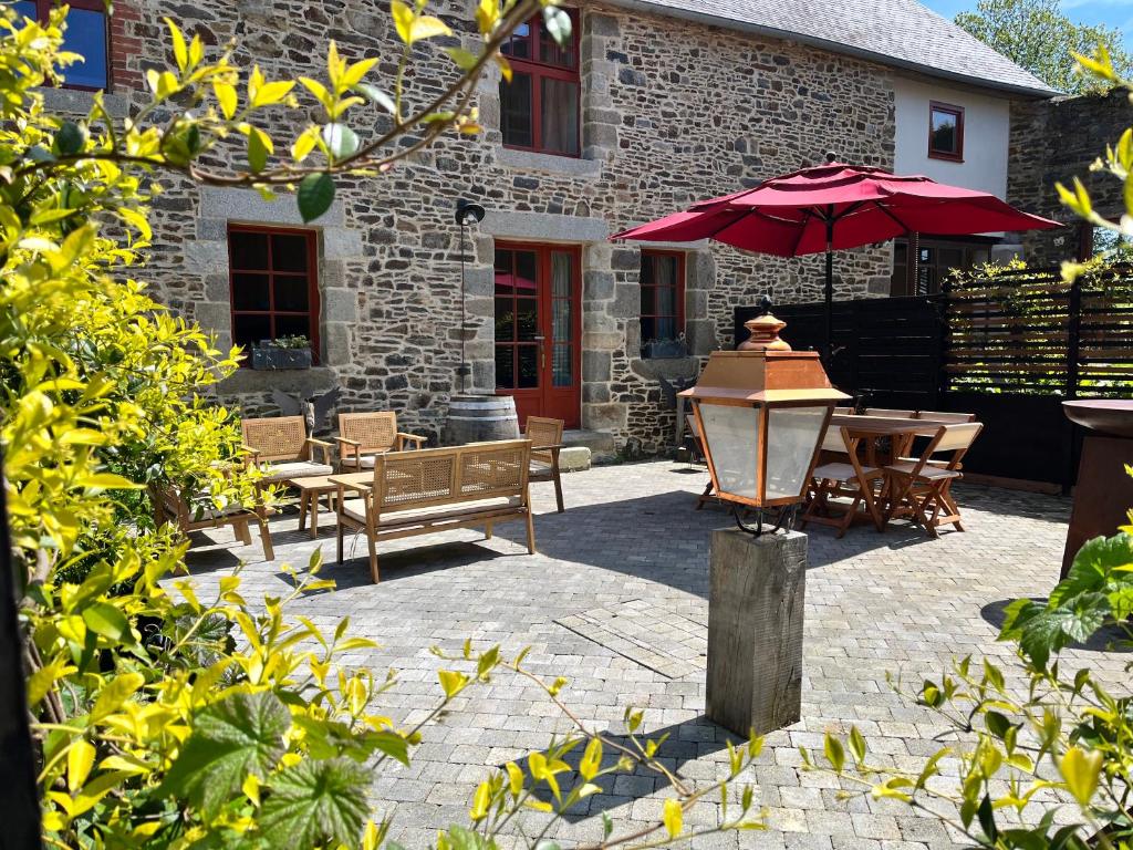 patio con tavolo e ombrellone rosso di Domaine du tertre ychot a Dol-de-Bretagne