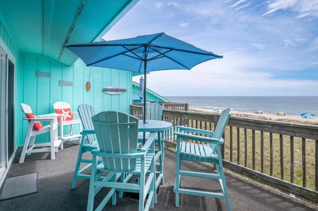 a patio with chairs and a table with an umbrella at Oceanfront with Pool - Winds VI in Carolina Beach