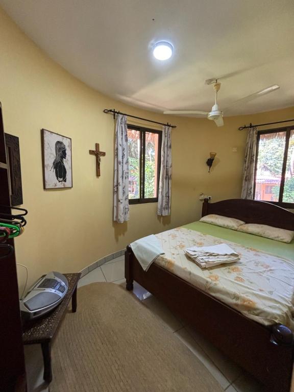um quarto com uma cama e uma cruz na parede em Joe's poolhouse em Mombaça