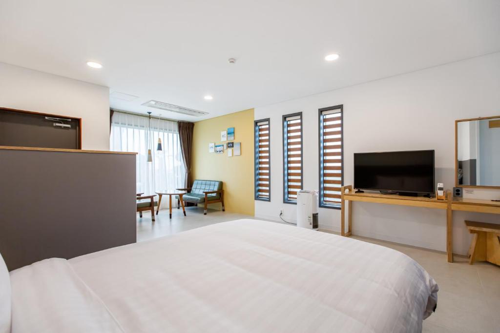 um quarto de hotel com uma cama e uma televisão em Lunamar Pension em Jeju