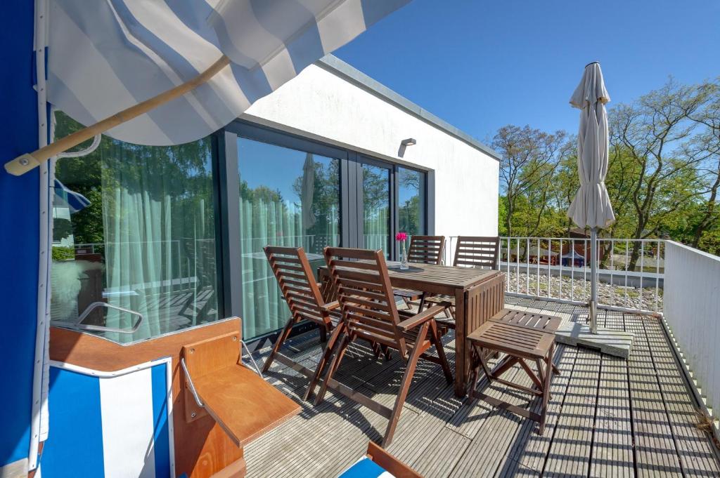 une terrasse avec une table, des chaises et un parasol dans l'établissement Haus Wetterhexe - FeWo 02, à Sellin