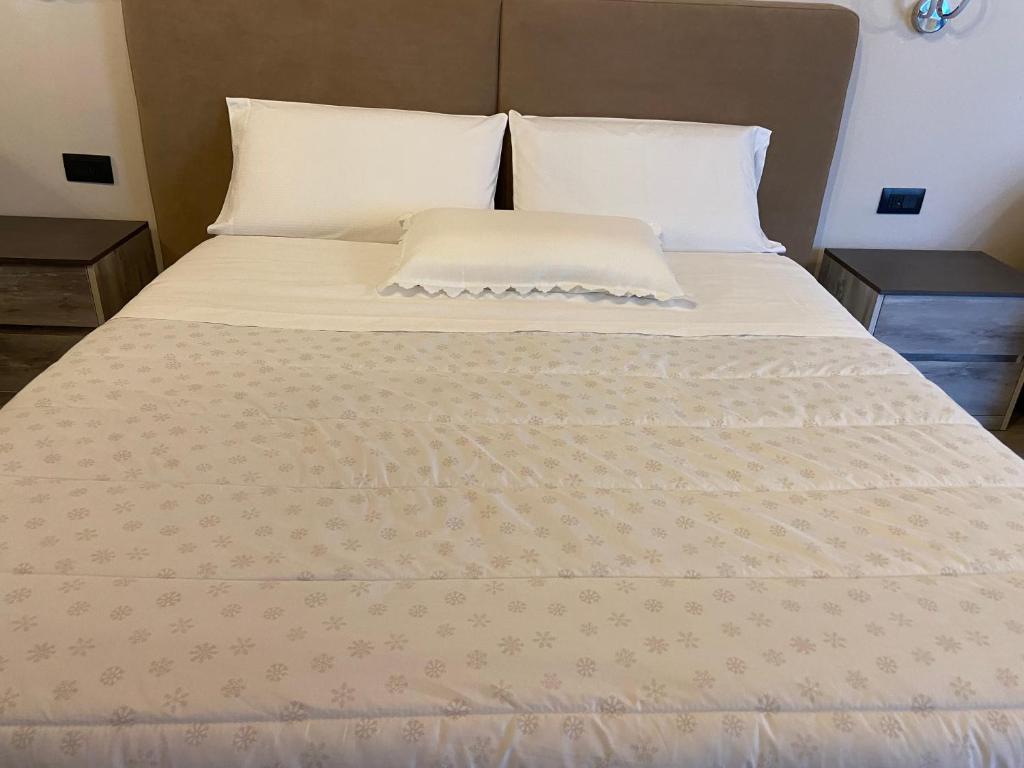 Una cama con sábanas blancas y almohadas. en Residenza Zotaj Small appartament, en Casale Monferrato