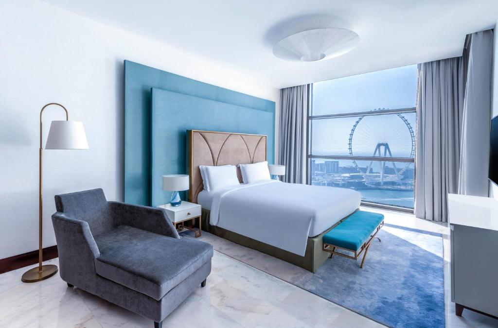 a bedroom with a bed and a chair and a window at Sofitel Dubai Jumeirah Beach in Dubai