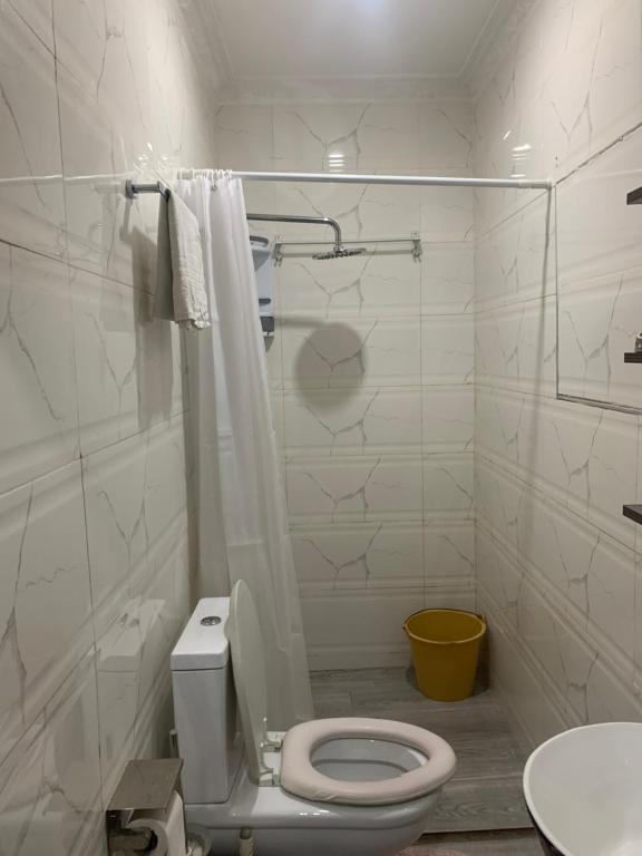 a white bathroom with a toilet and a sink at M&C homes Akrowa in Accra