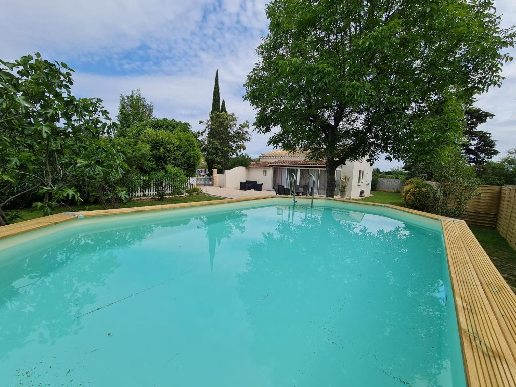 a large blue swimming pool in front of a house at L'Ecrin des Alpilles in Graveson