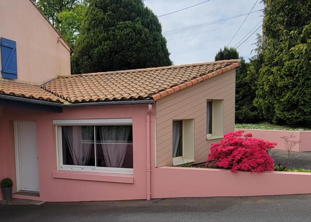 ein rosa Haus mit einem Fenster und einem rosa Busch in der Unterkunft Studio 6 in Le Boupère
