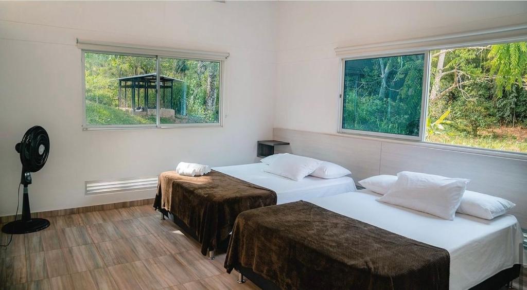 two beds in a room with two windows at Eco Hotel Montenegro in Medellín
