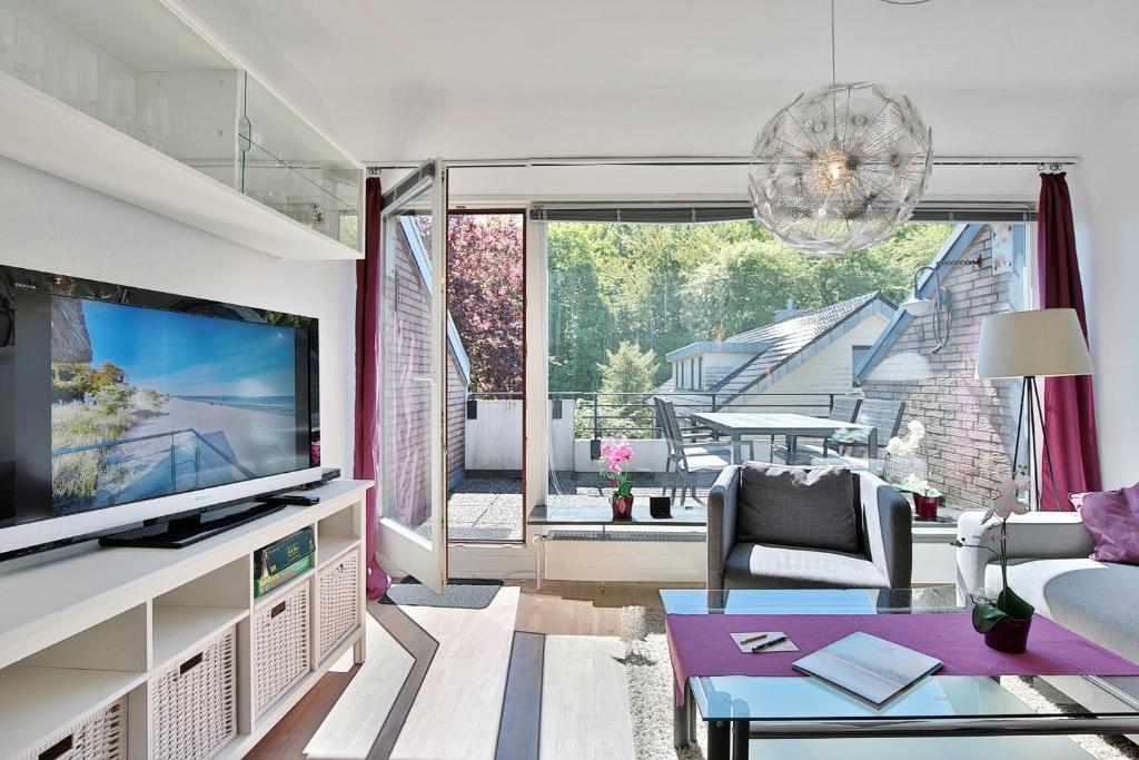 ein Wohnzimmer mit Fernseher, Couch und Tisch in der Unterkunft Haus Adria Haus Adria Appartement 29 in Scharbeutz