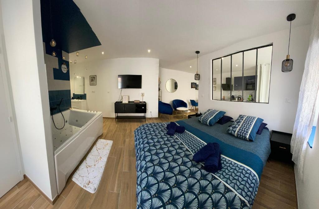 um quarto com uma cama azul e uma banheira em Cosy Appart’ & spa - Appartement privatif - baignoire balnéothérapie 