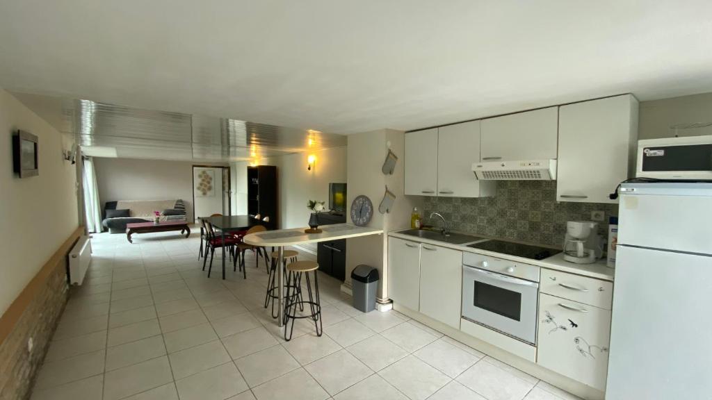 een keuken met witte kasten en een tafel en stoelen bij Les Landes avec Terrasse et Jardin in Heuringhem