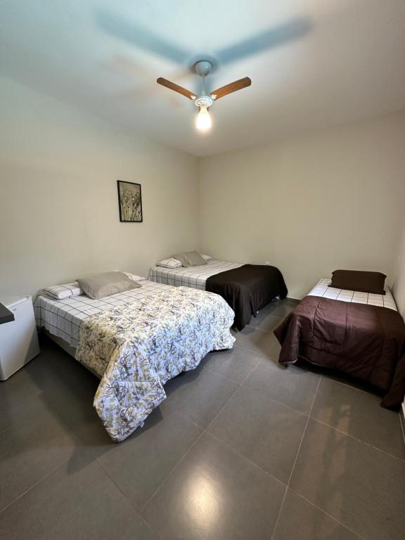 um quarto com 2 camas e uma ventoinha de tecto em casa inteira com 3 suites e área de lazer em Delfinópolis