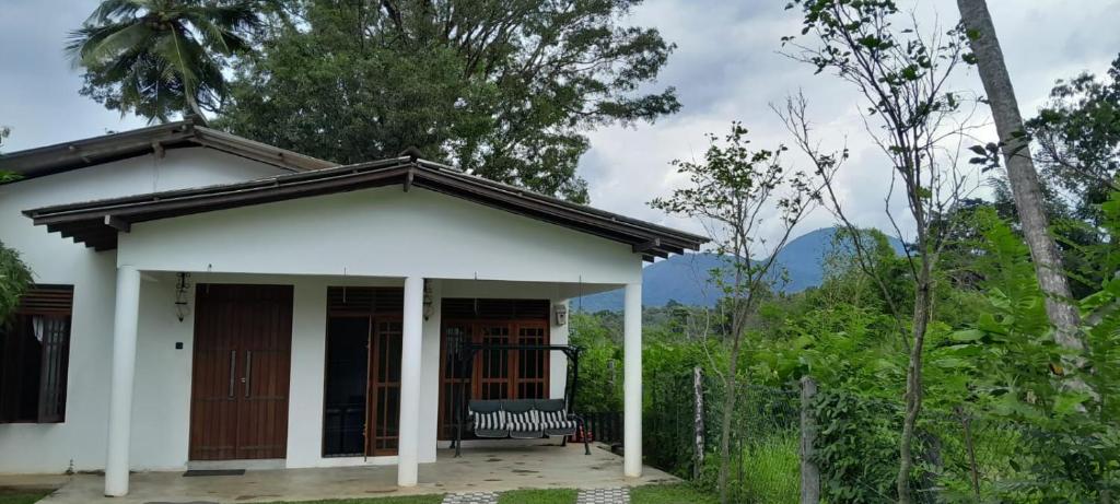 une petite maison blanche avec un banc sur la terrasse couverte dans l'établissement Meegahasewana Bungalow, à Kurunegala