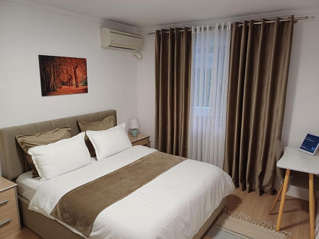 a bedroom with a large bed and a window at Regis Apartment in Tirana