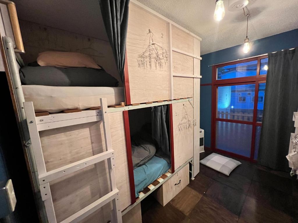 a room with two bunk beds and a window at Toyako Guest House Ponkotan in Lake Toya