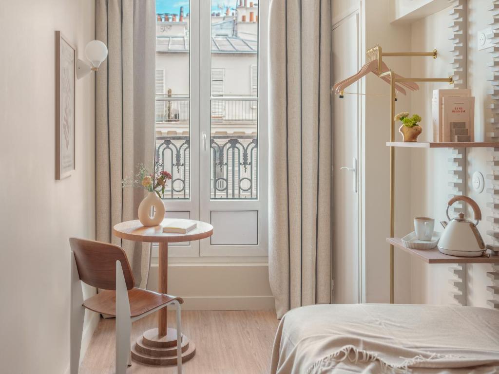 Zimmer mit einem Bett, einem Tisch und einem Fenster in der Unterkunft Hôtel Basss in Paris