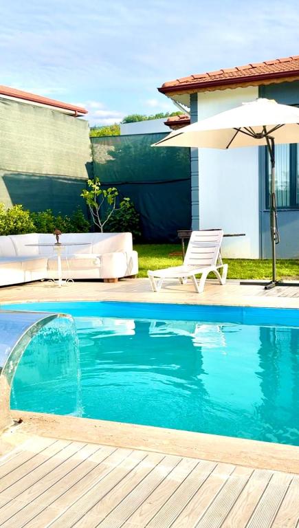 a swimming pool with a chair and an umbrella at Begonvil Konaklama in Sapanca