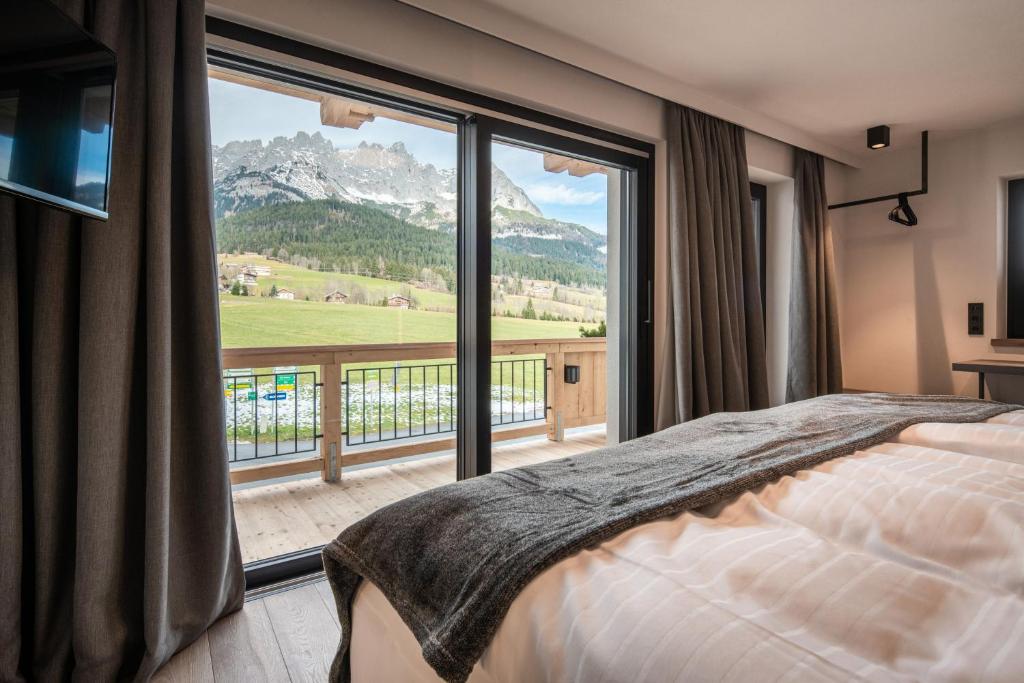 a bedroom with a bed and a large window at KaiserMoments in Going am Wilden Kaiser