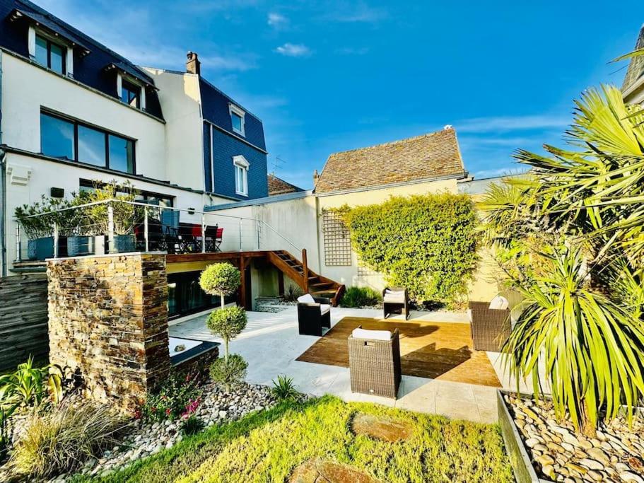 une grande maison blanche avec une cour ornée de plantes dans l'établissement MAISON 4 CHAMBRES,JARDIN ET TERRASSE, proche mer,casino et place Morny, à Deauville