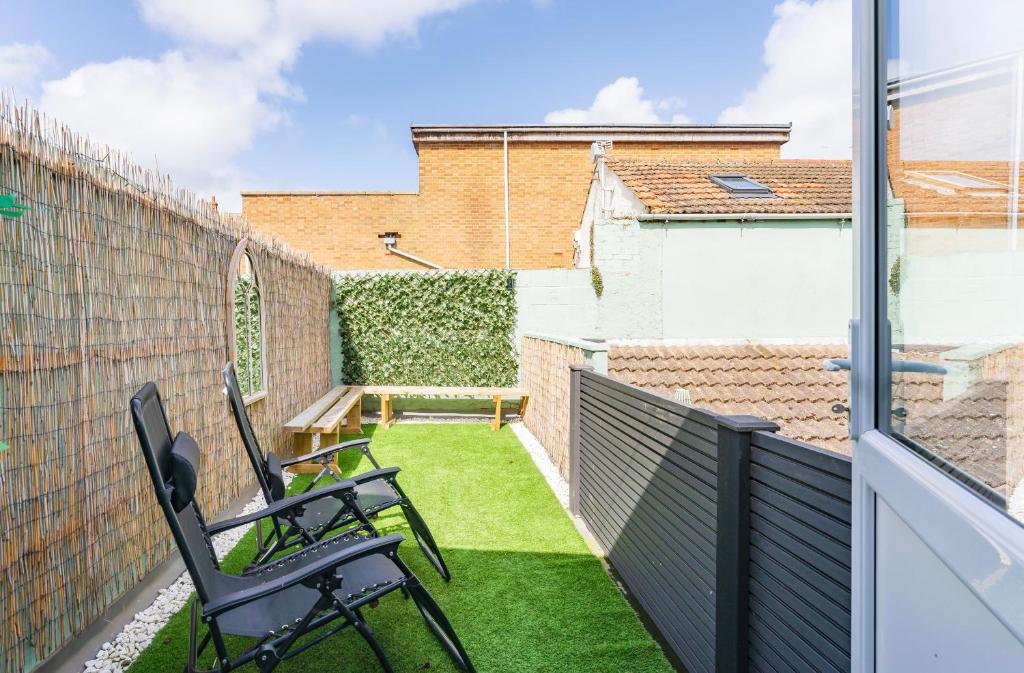a small balcony with two chairs and grass at The Cottage at Logan Lodge in Great Yarmouth