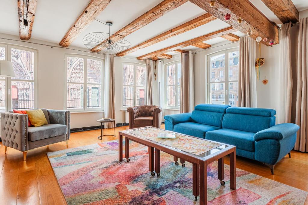 un salon avec des chaises bleues et une table dans l'établissement La Place de la Cathédrale - Superbe appt face à la Cathédrale, à Strasbourg