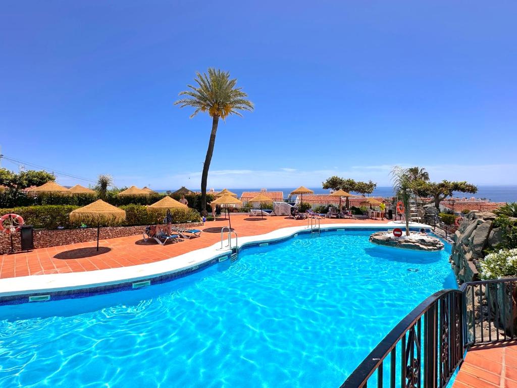 una piscina en un complejo con palmeras en Los Naranjos 25A Private Pool Capistrano Village, en Nerja