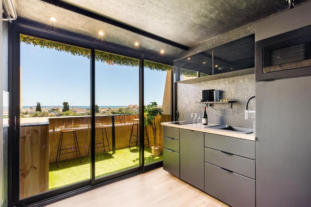une cuisine avec une grande fenêtre offrant une vue dans l'établissement L'écrin noir Port nature, au Cap d'Agde