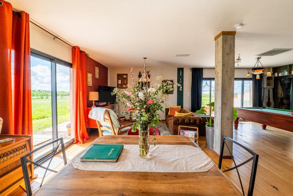 a dining room with a table with a vase of flowers at La Grange des Anges in Blanc