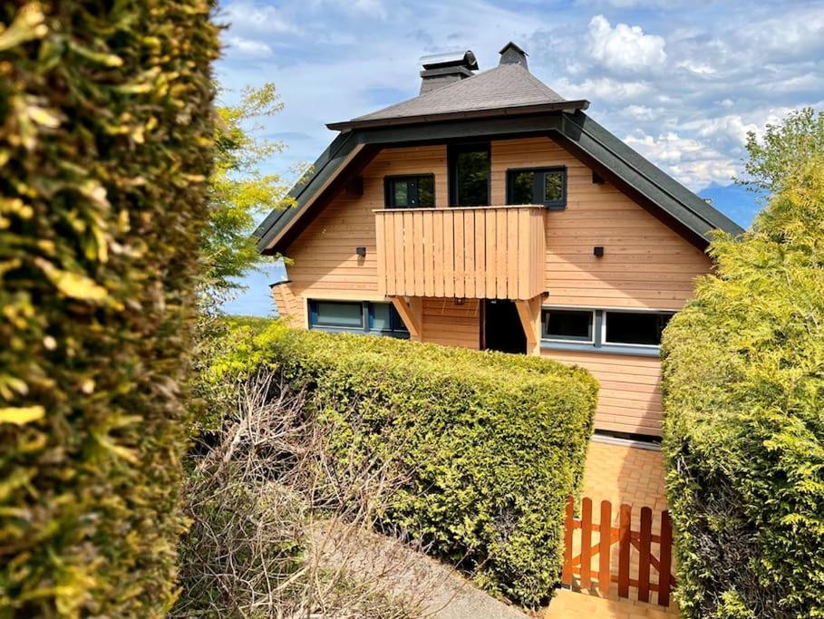 a wooden house with a balcony and bushes at La Barque in Thollon