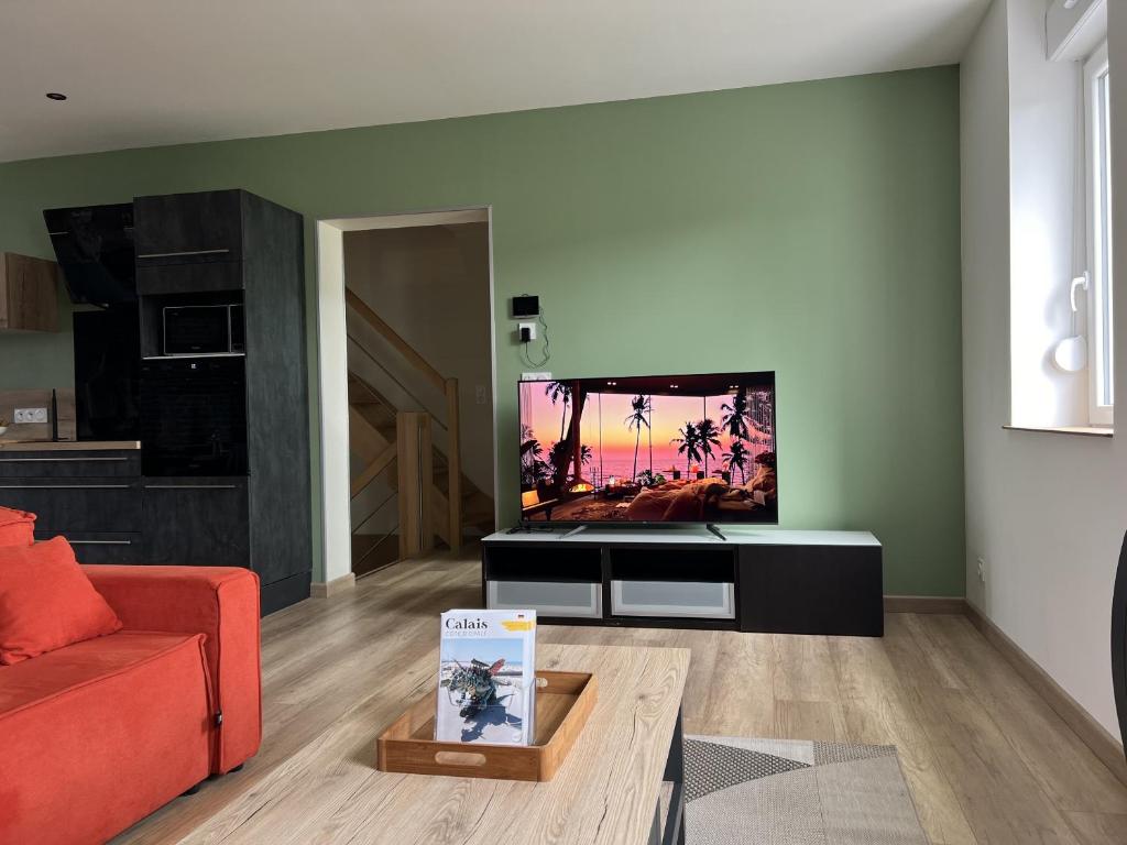 un salon avec une télévision à écran plat sur un meuble dans l'établissement Le Victor Hugo, à Calais