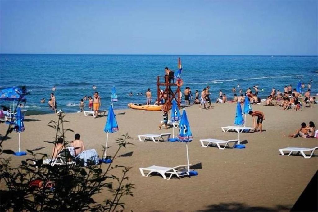 eine Gruppe von Personen am Strand mit Stühlen und Sonnenschirmen in der Unterkunft Kanarya Apart in Trabzon