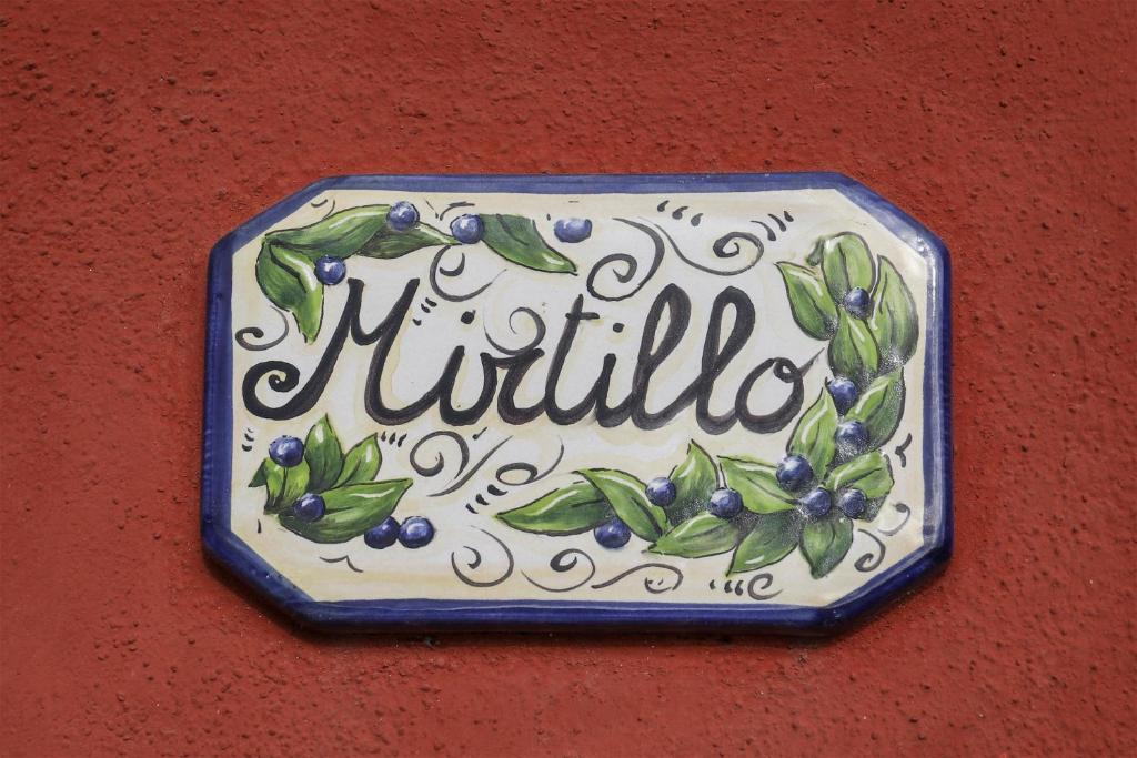 un cartello su un muro con dei mirtilli sopra. di MIRTILLO di Home Hill a Lucca