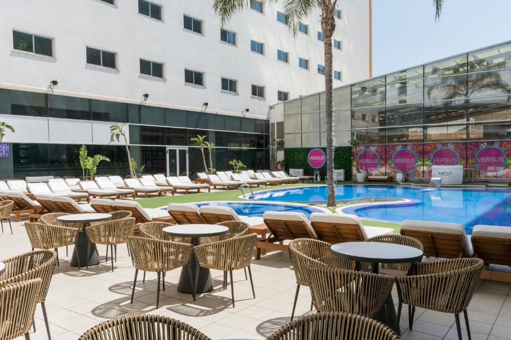 um pátio do hotel com mesas e cadeiras e uma piscina em VS Gandía Palace Hotel **** em Gandia